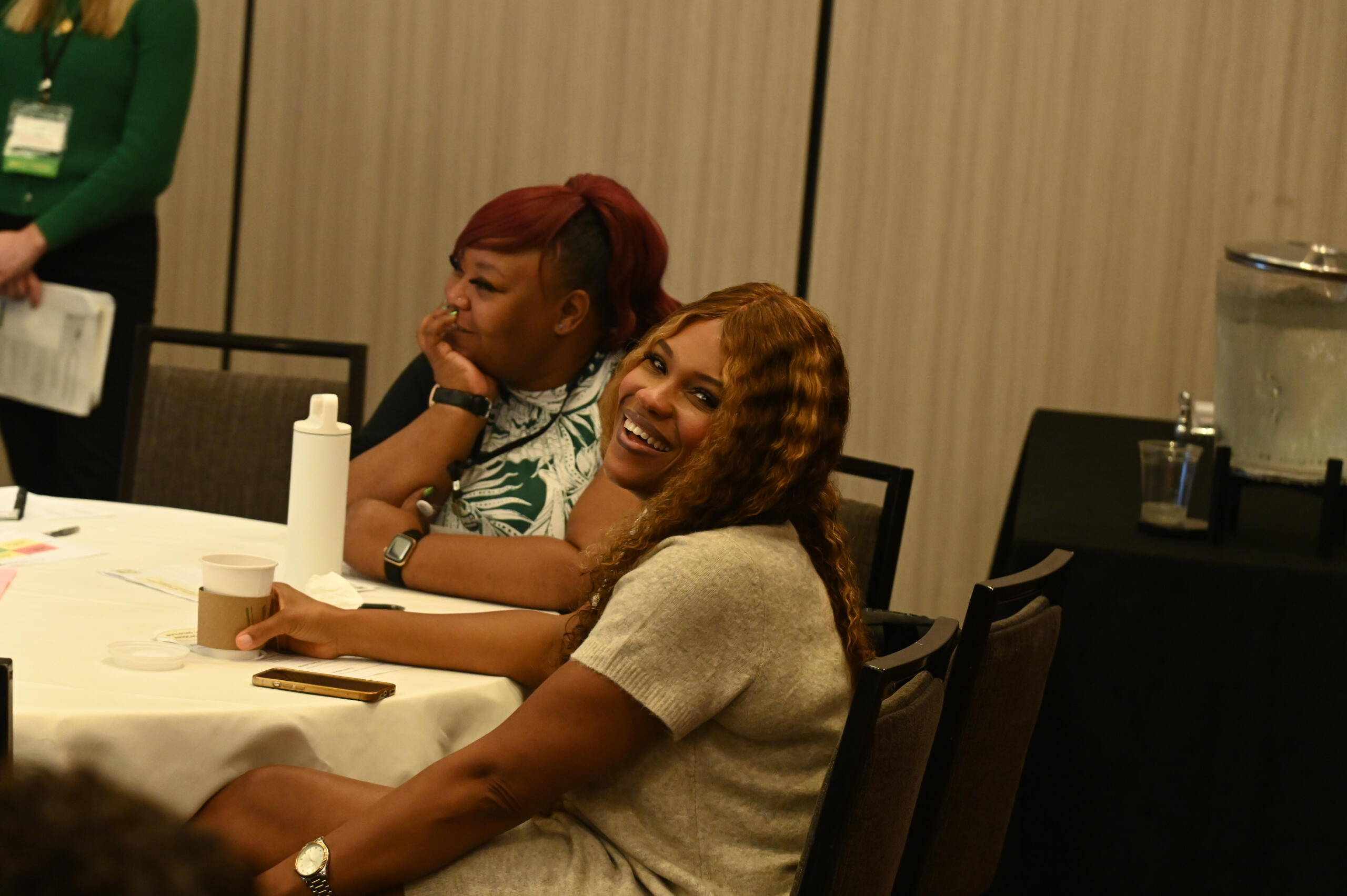 Two women laughing during a community-focused workshop — candid moment showing warmth, connection, and authentic engagement.